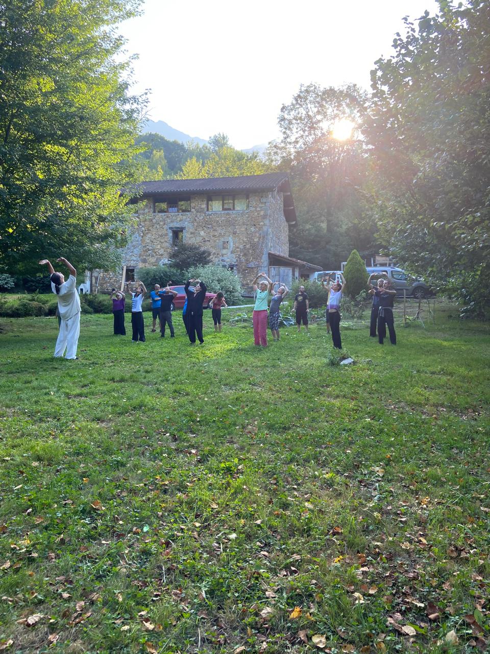 Group practising at dusk in front of the stone house